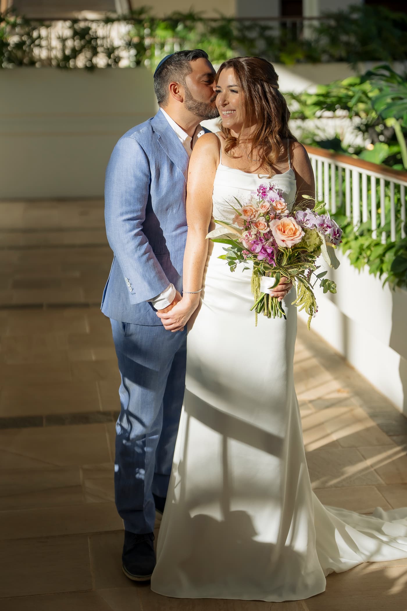 Jake kissing Becca on the cheek, bouquet in hand