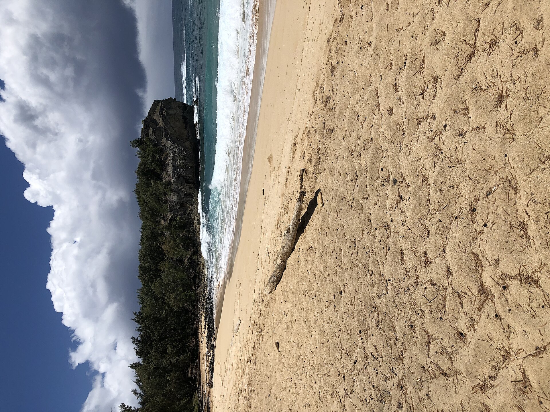The broad golden sweep of Shipwreck Beach on Kaua'i's south shore with the Makawehi cliff rising at the far end