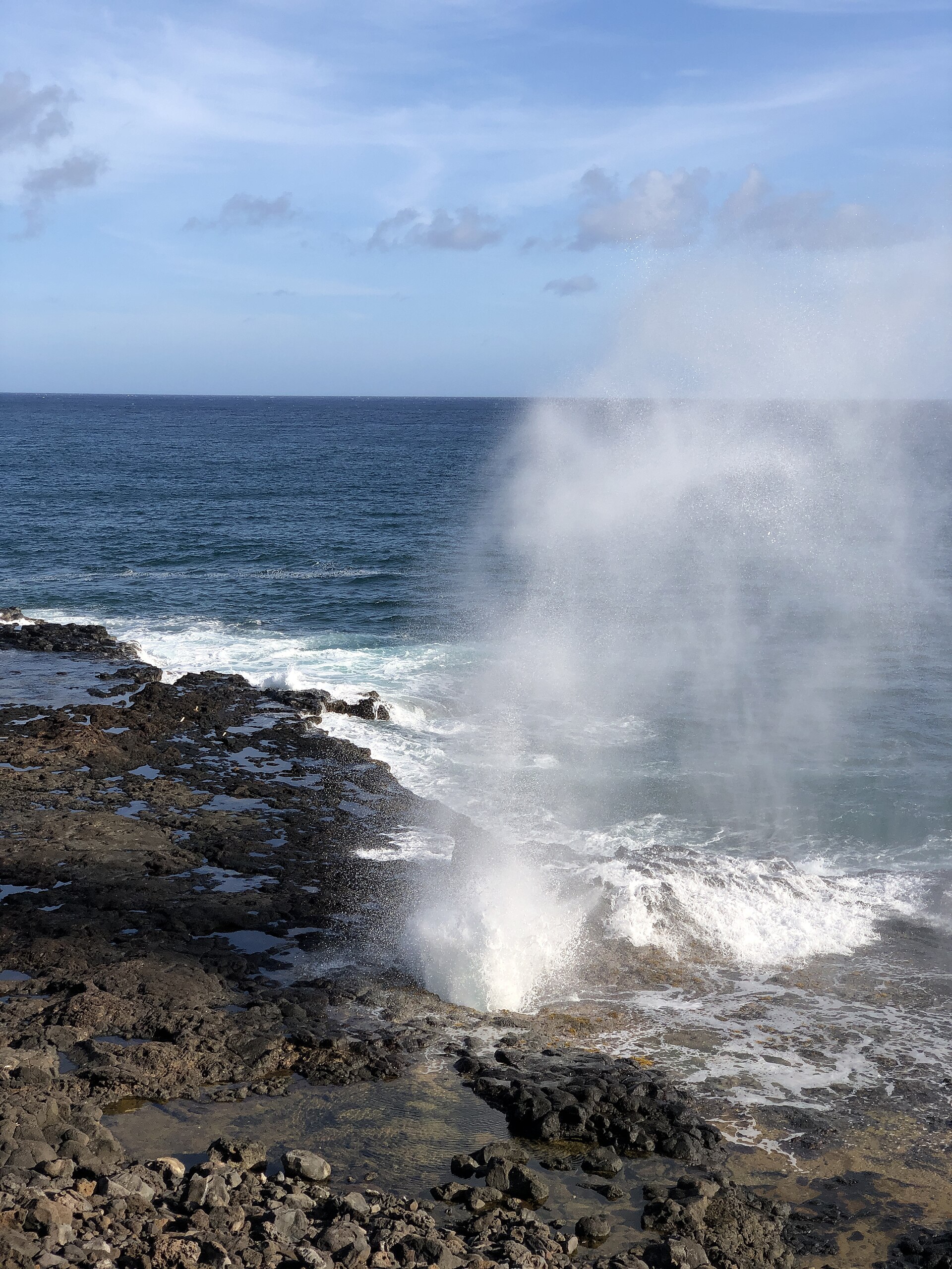 The Spouting Horn blowhole on Kaua'i's south shore erupting in a tall plume of white spray